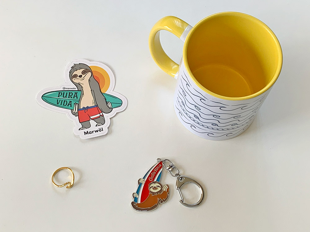 コスタリカのサーフィンをモチーフにしたお土産。波柄のマグカップと指輪。ナマケモノとサーフボードがモチーフのステッカー＆キーホルダー。