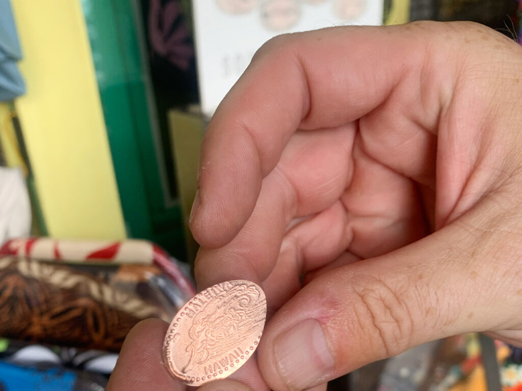 ペニー(1セント硬貨)に「Haleiwa」マークを刻印。手の後ろに刻印機。